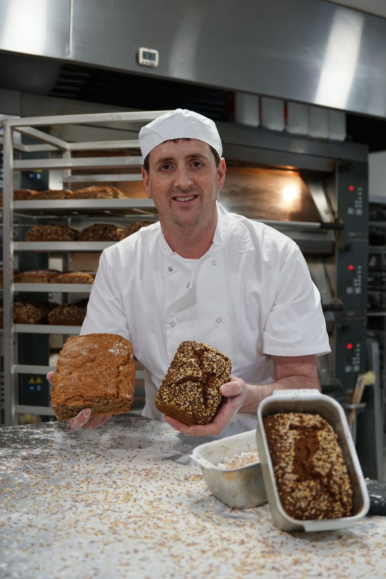 A plain brown soda loaf held next to a seeded loaf